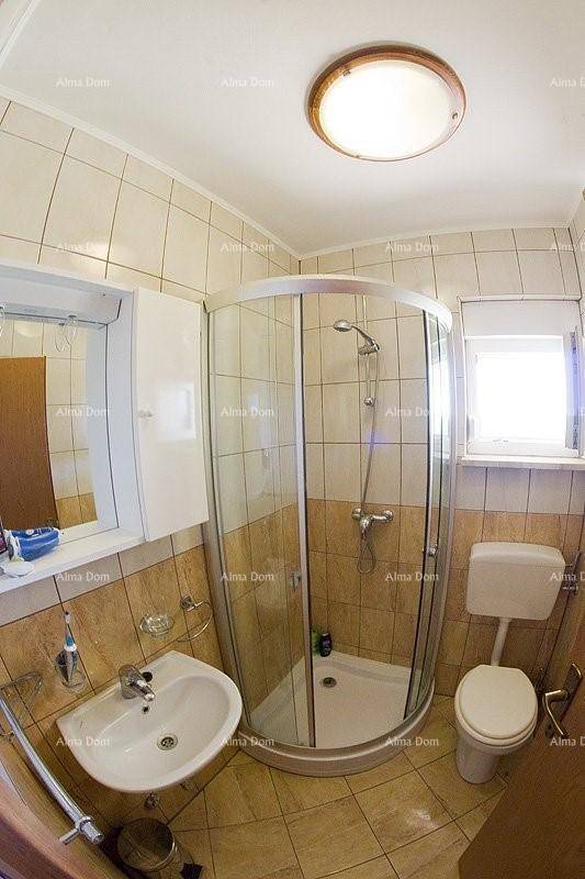Kleines Badezimmer mit Duschkabine, WC, Waschbecken und Fenster für Tageslicht.