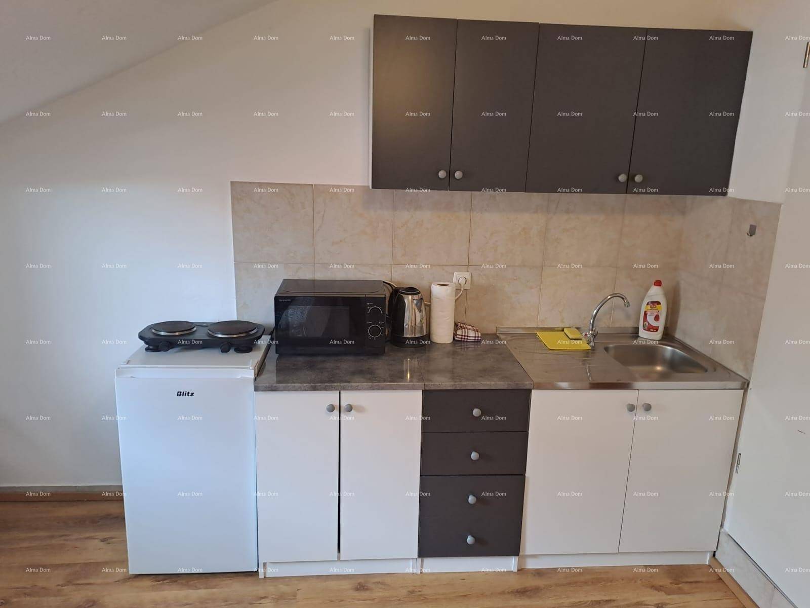 Detaillierte Ansicht der Küchenzeile mit Kühlschrank, Mikrowelle und Kochplatten.
