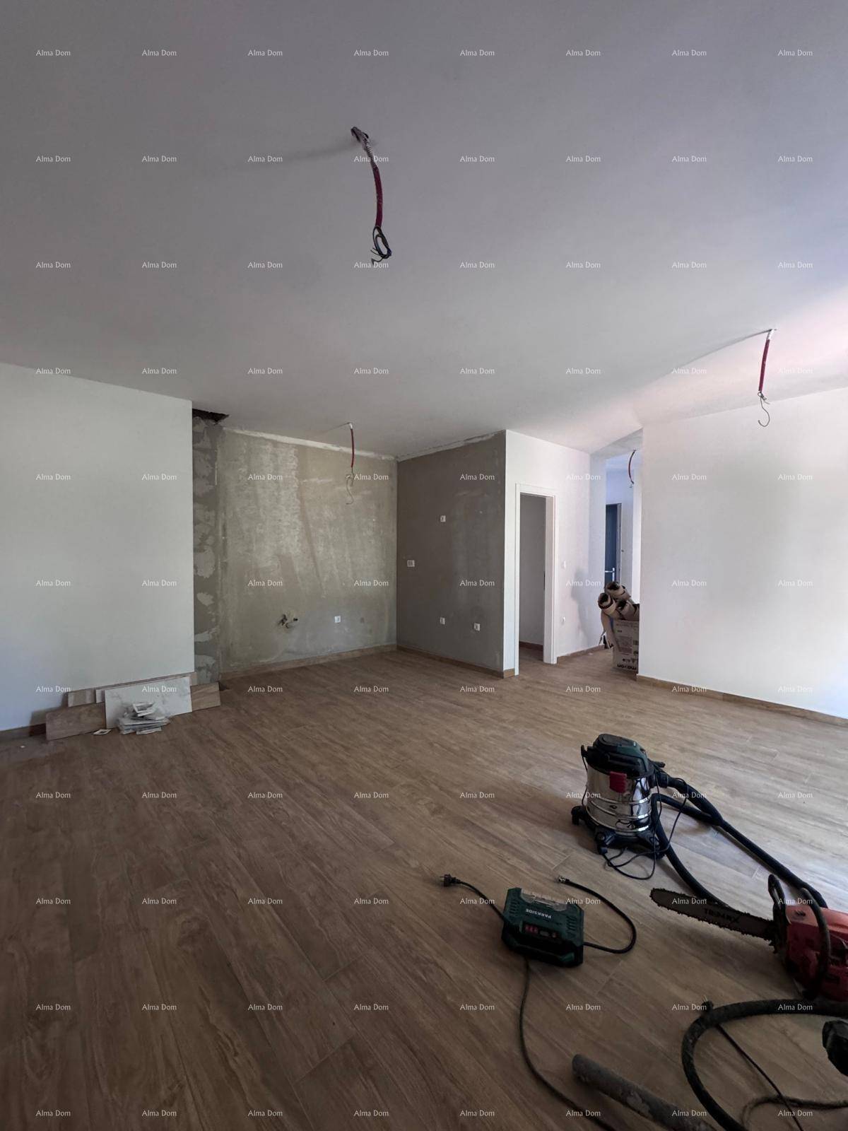 Geräumiger Innenraum im Rohbau mit Holzboden und teilweise verputzten Wänden, bereit für den Ausbau.