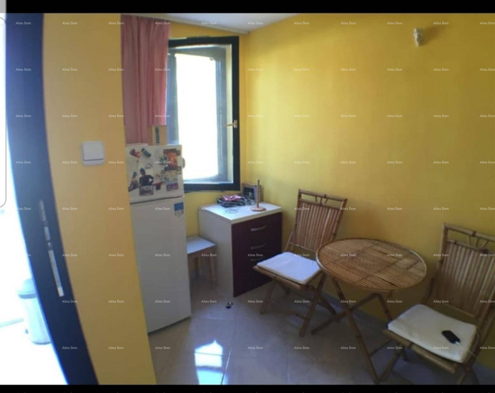 Küche mit Kühlschrank, Fenster, kleinem Tisch und gelben Wänden.