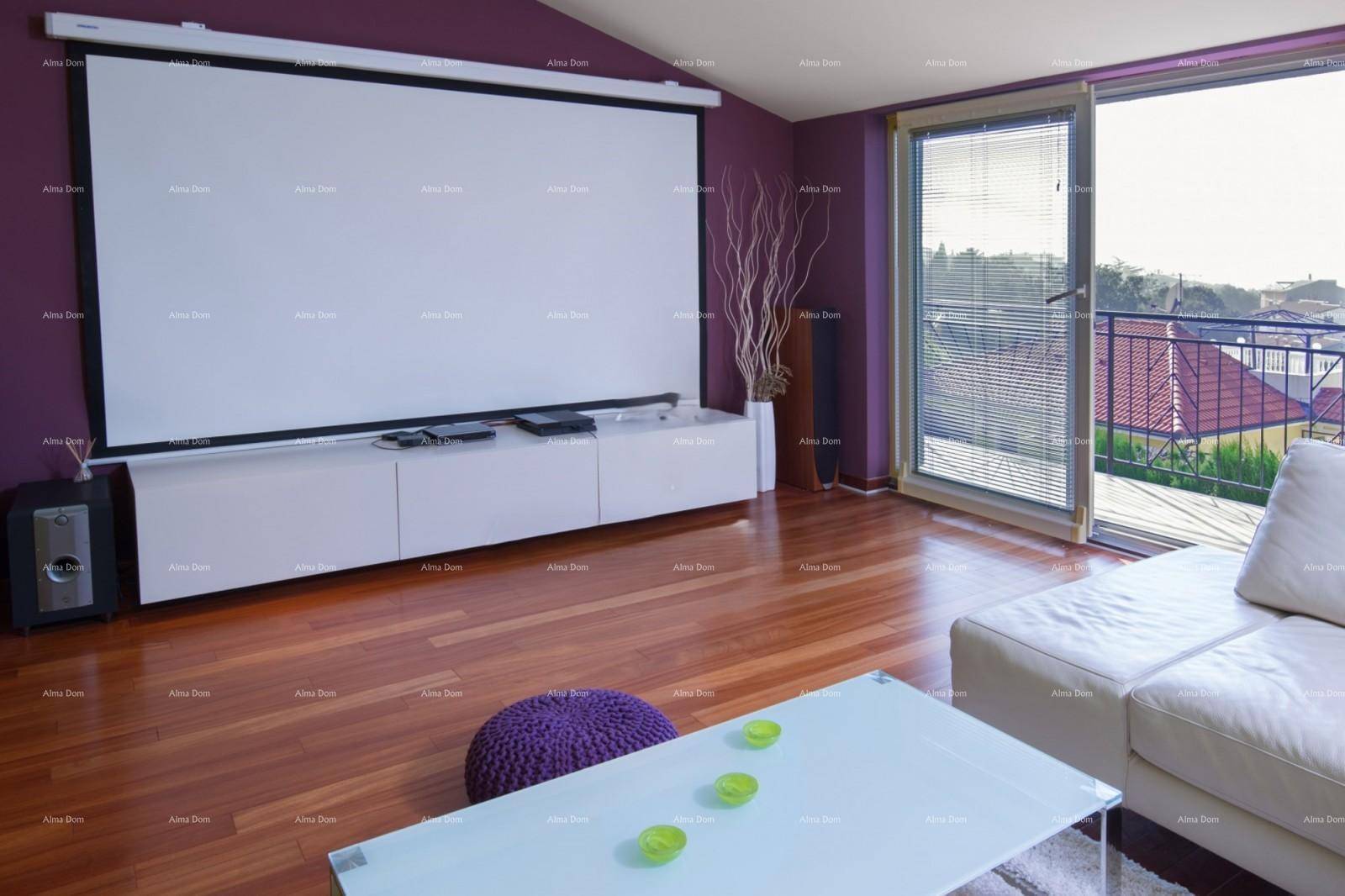 Wohnbereich mit großem Projektionsbildschirm, Holzboden und Zugang zum Balkon.