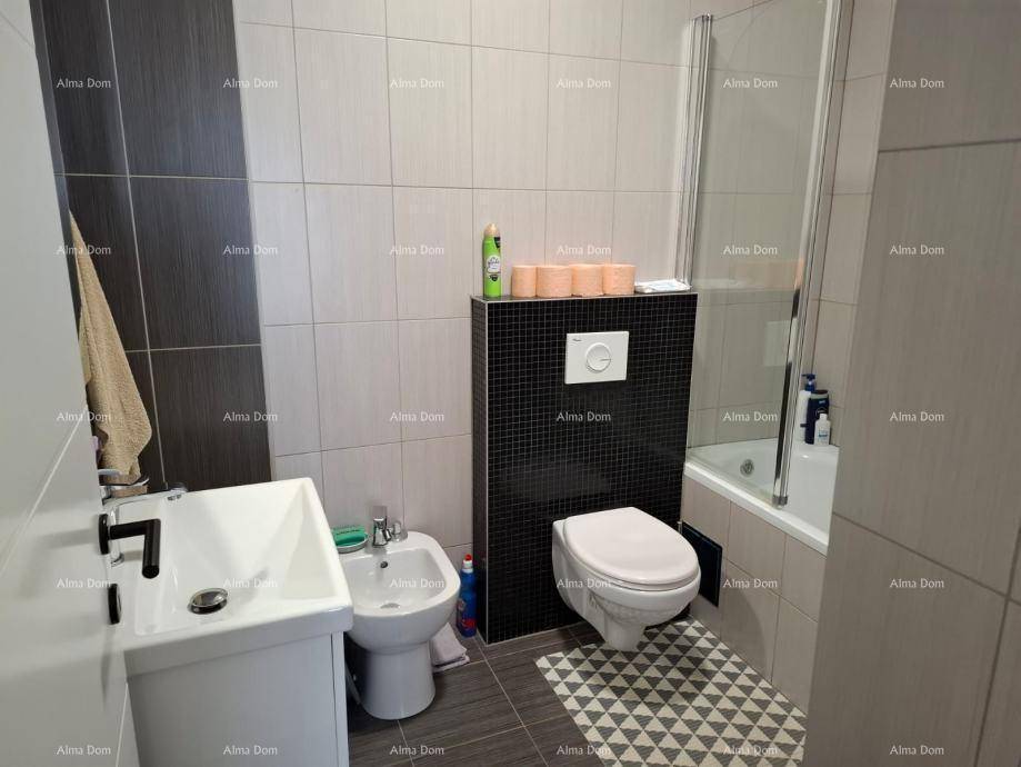 Modernes Badezimmer mit Badewanne, Duschwand, Bidet und Wand-WC in Grautönen.