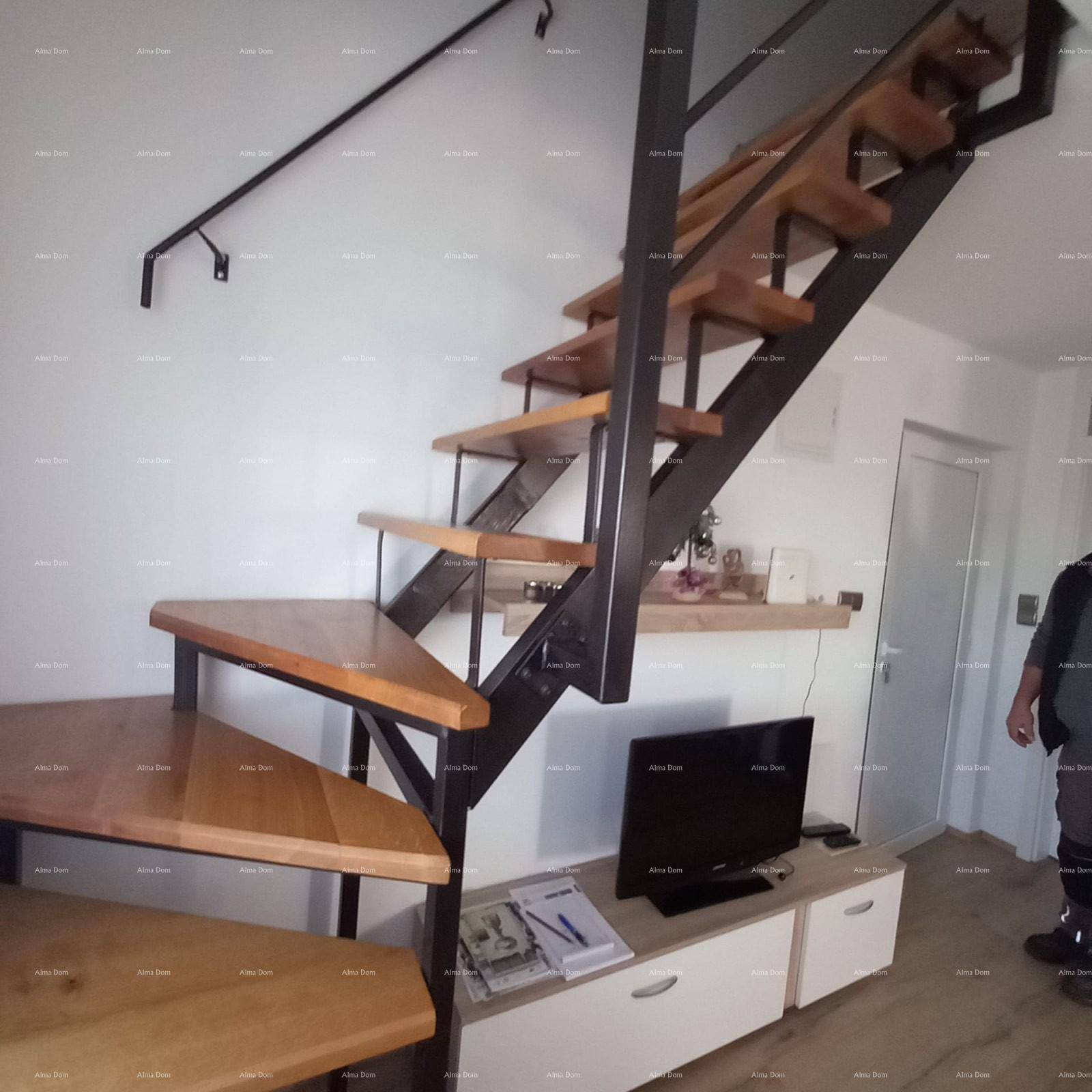 Moderner Wohnbereich mit offener Holztreppe und TV-Möbeln.
