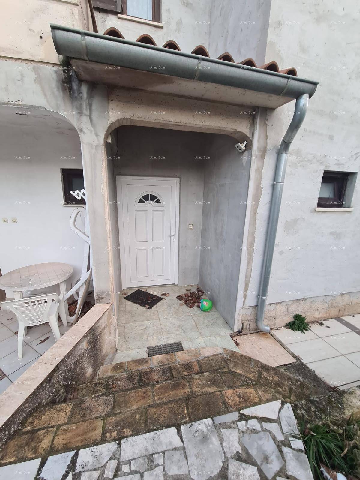 Eingangsbereich eines Hauses mit weißer Tür, Treppe und kleiner Terrasse.
