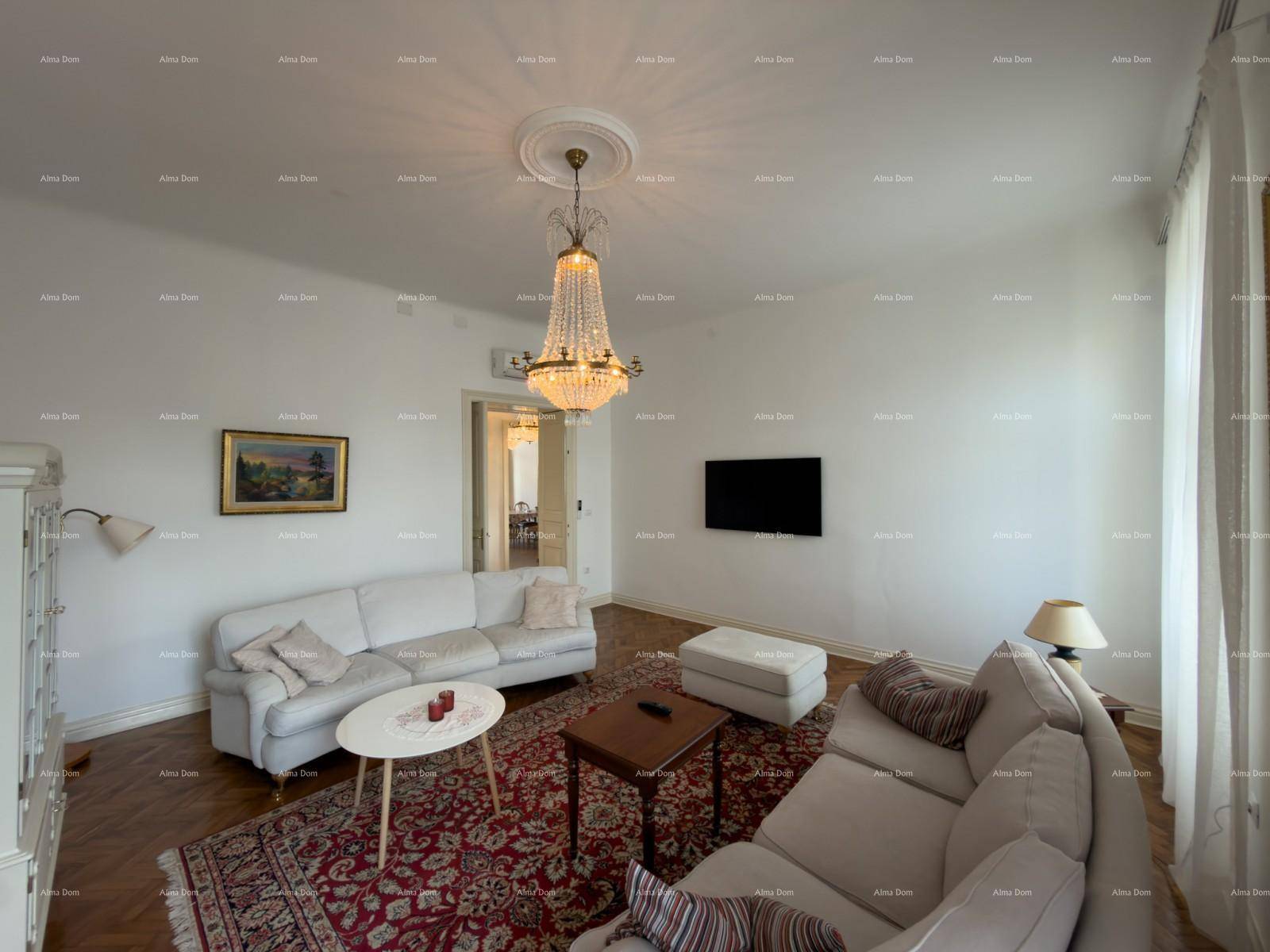 Gemütliches Wohnzimmer mit Wandfernseher, Klimaanlage und einem opulenten Kronleuchter als Blickfang.