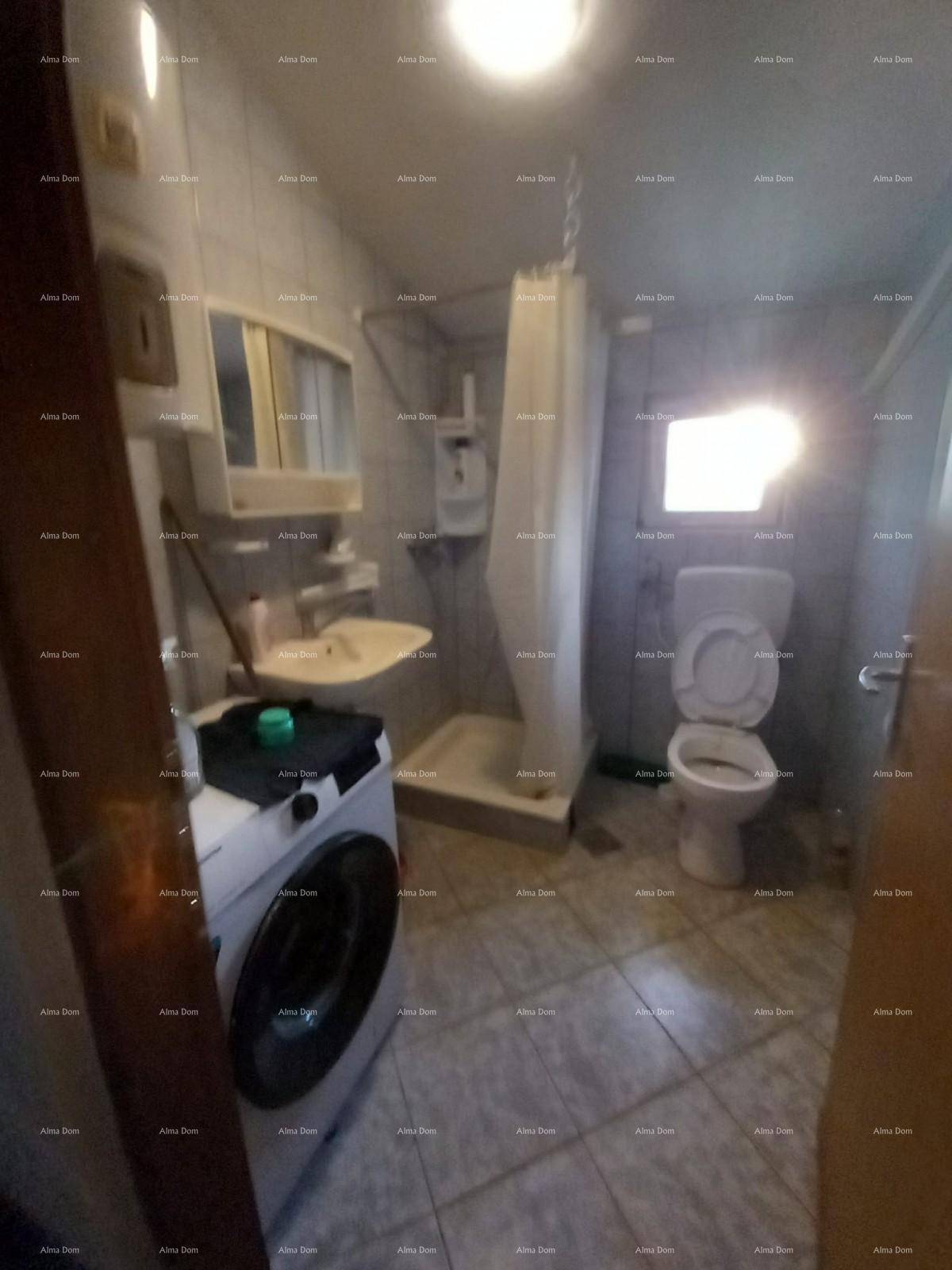 Kleines Badezimmer mit Dusche, WC, Waschbecken und Waschmaschine, gefliest in hellen Tönen.
