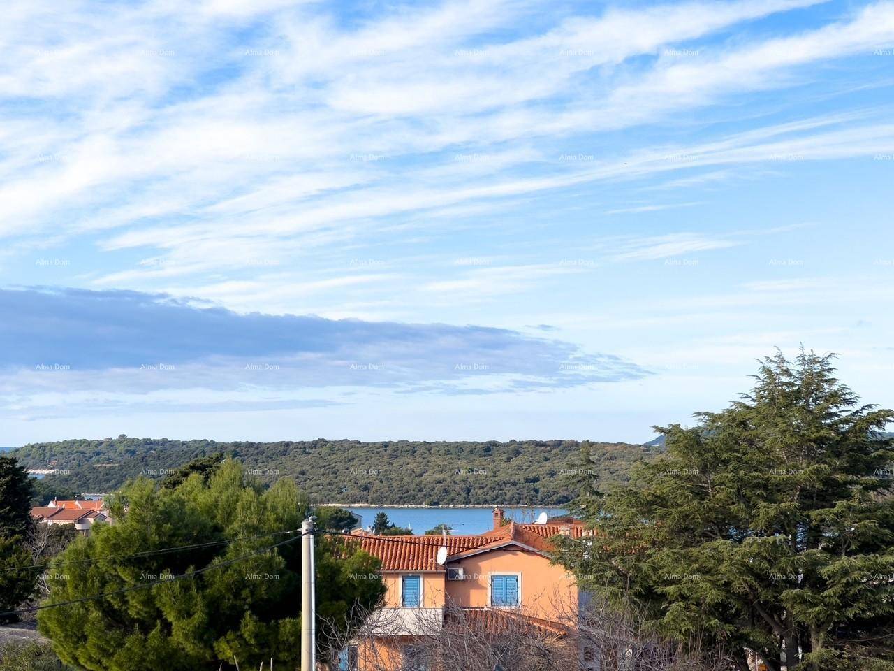 Panoramablick auf das Meer und die grüne Landschaft mit traditionellen Dächern im Vordergrund.