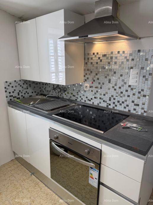 Kompakte moderne Küche mit weißen Hochglanzschränken, Induktionskochfeld und Mosaikfliesen als Spritzschutz.