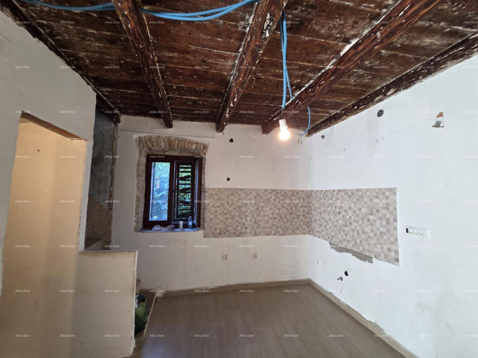 Raum im Rohbau mit Fliesenboden, sichtbaren Holzbalken und einer gefliesten Wandfläche.