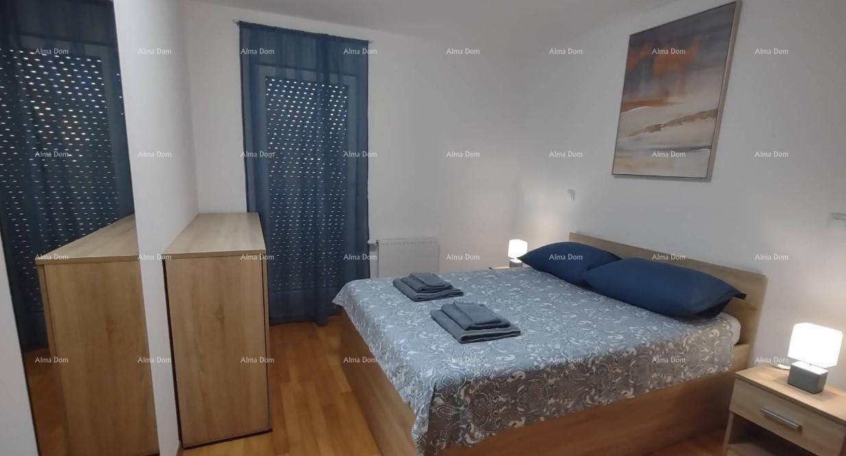 Helles Schlafzimmer mit Doppelbett, Holzmöbeln, Parkettboden und blauen Vorhängen am Fenster.