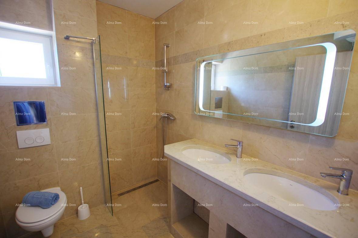 Elegantes Badezimmer mit doppelten Waschbecken, beleuchtetem Spiegel und gefliesten Wänden.