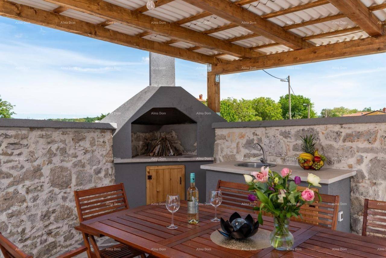 Gemütlicher Grillbereich im Freien mit eingebautem Grill, Spülbecken und Esstisch unter einer schattenspendenden Pergola.