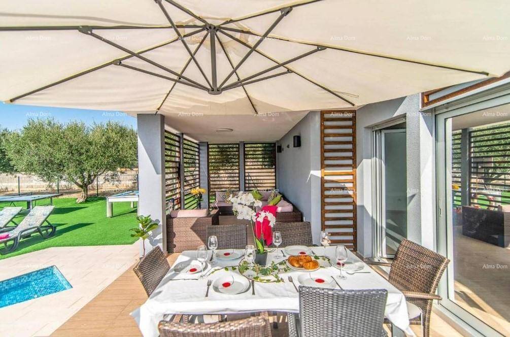 Großer Esstisch auf der Terrasse unter einem Sonnenschirm, mit Zugang zum überdachten Loungebereich.