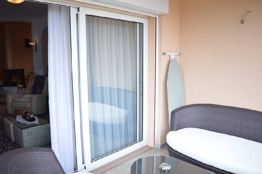 Gemütlicher Balkon mit Sitzgelegenheiten und Blick durch die Schiebetür ins Wohnzimmer.