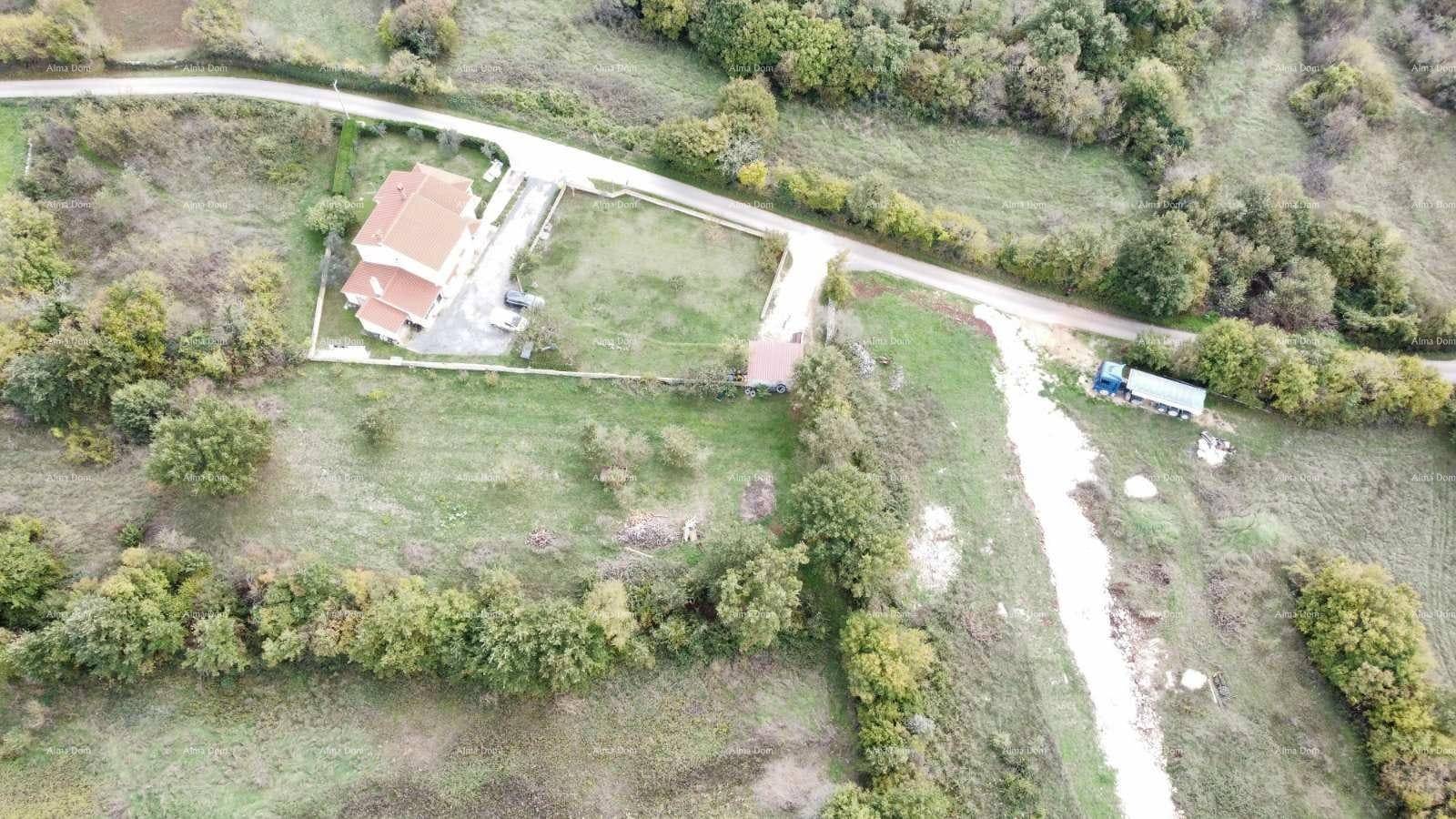 Draufsicht auf ein Anwesen mit rotem Dach, Rasenfläche, Zufahrtsstraße und umgebender Natur.