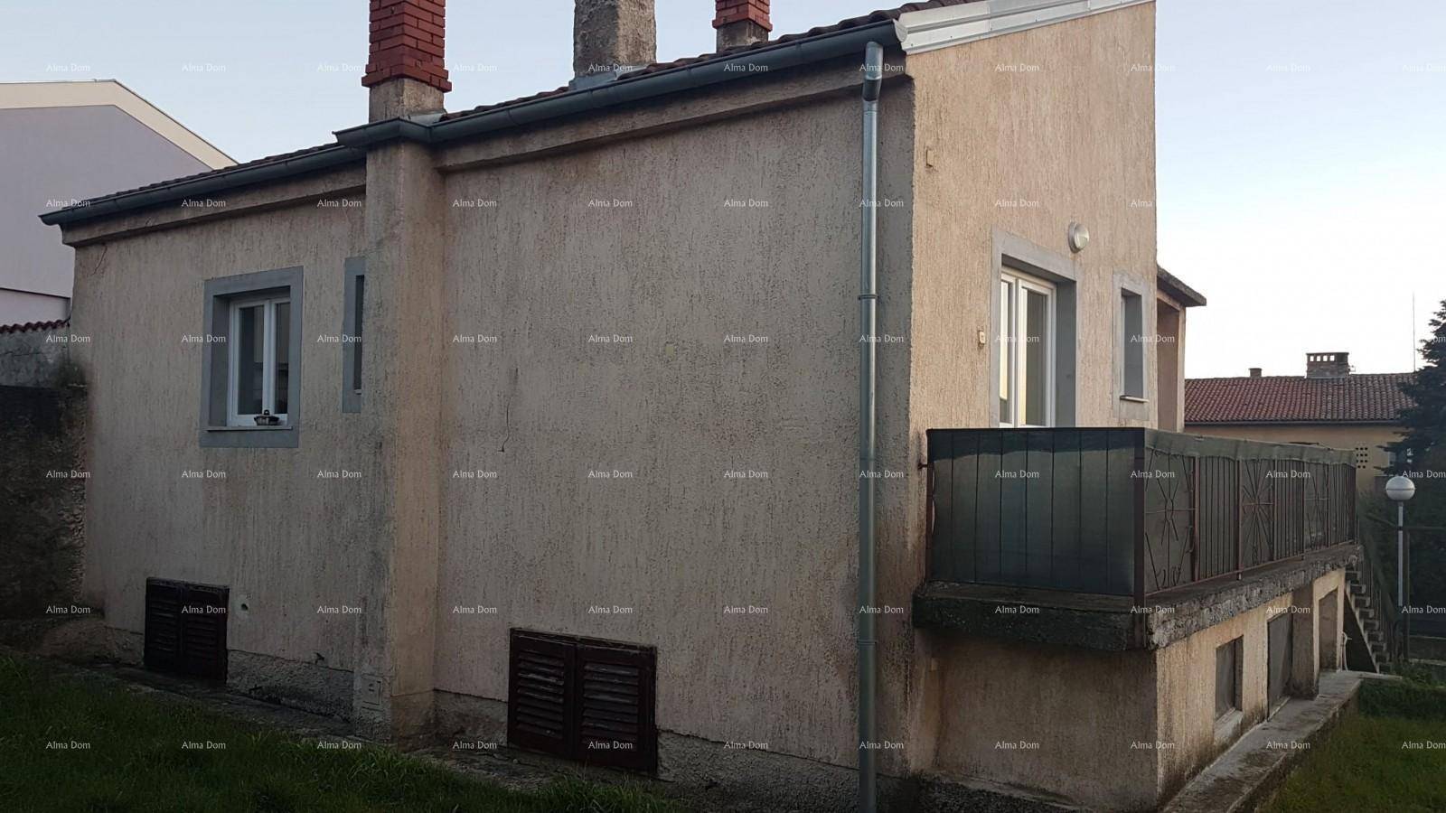 Seitenansicht des Hauses mit Fenstern, einem kleinen Balkon und der strukturierten Fassade.