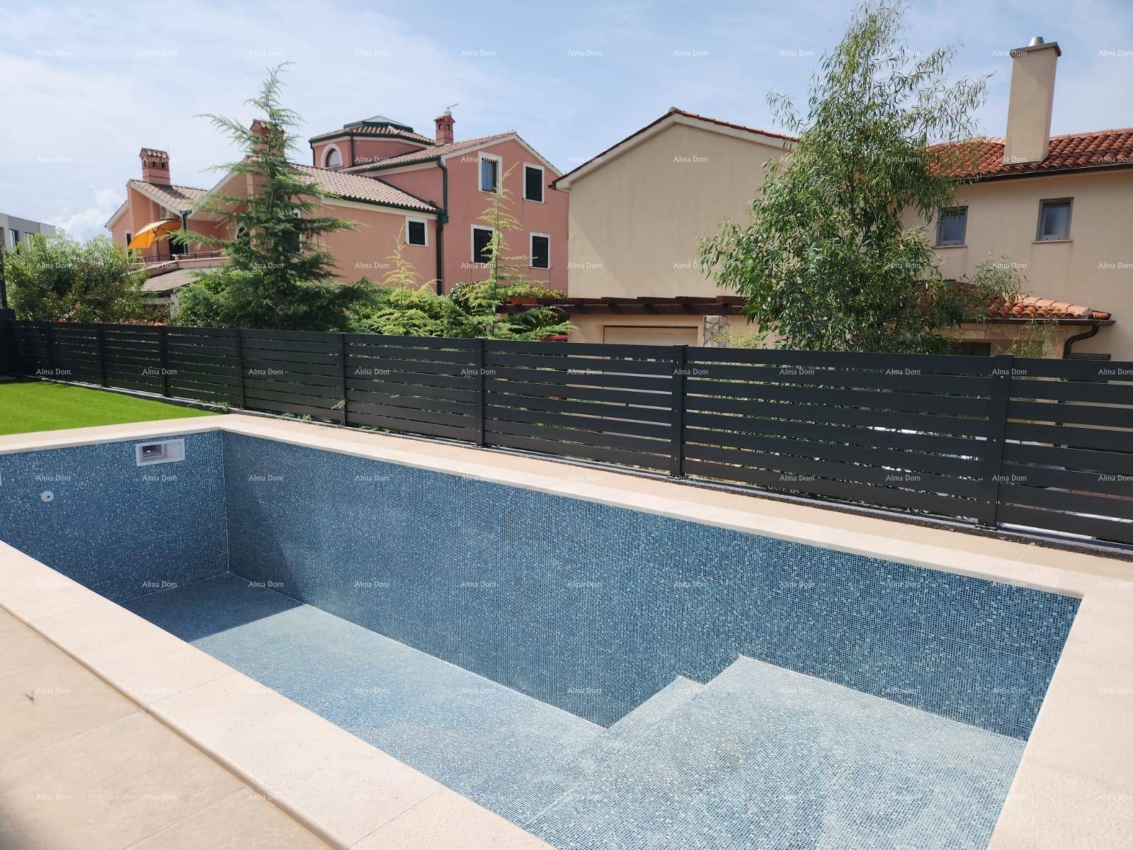 Leerer Swimmingpool mit blauen Mosaikfliesen, umgeben von einem modernen Zaun und Nachbarhäusern.