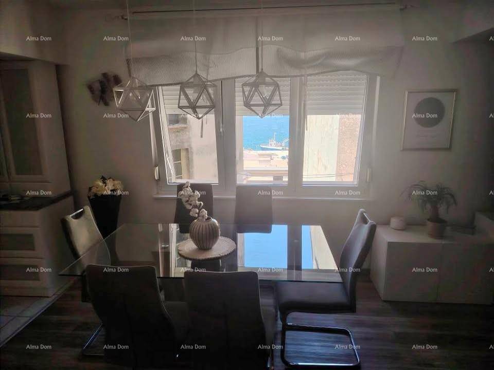 Essbereich mit modernem Glastisch und Stühlen, bietet einen seitlichen Blick auf das Meer durch das Fenster.