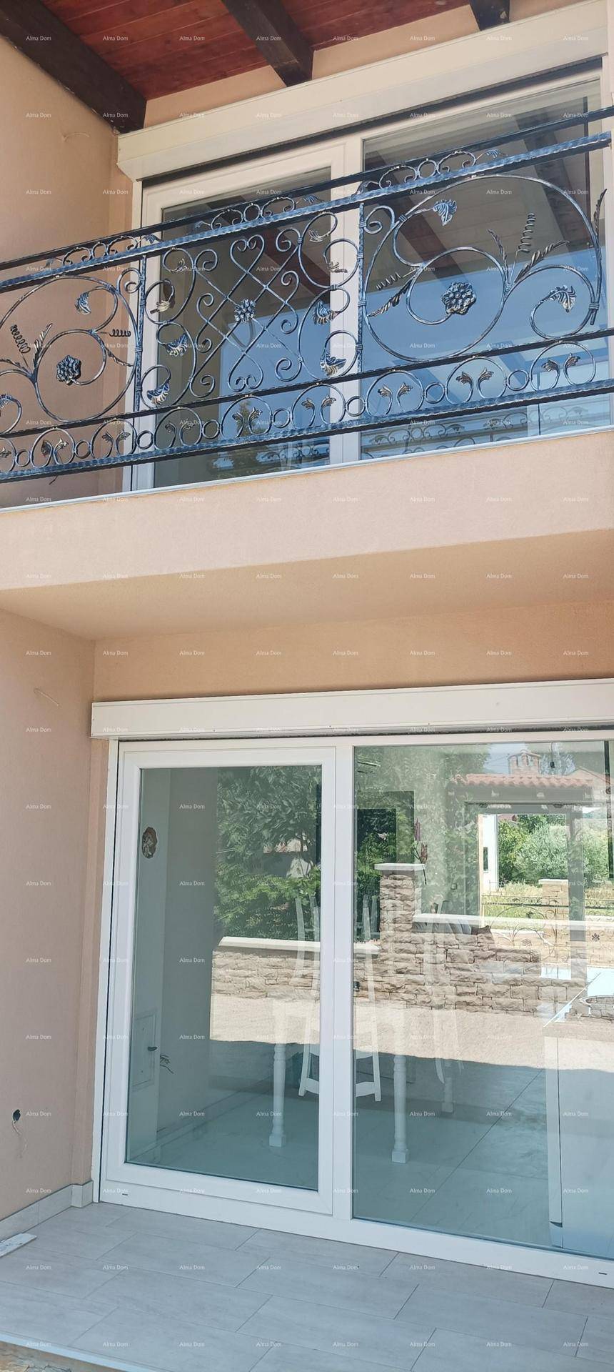 Fassadendetail mit Balkon im Obergeschoss und großen Schiebetüren im Erdgeschoss.