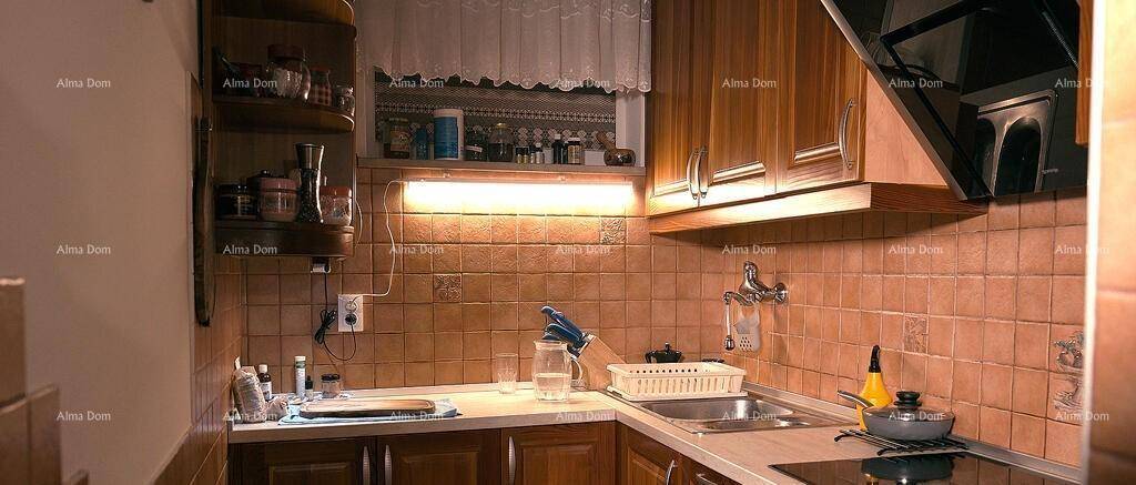 Funktionale Küche mit Holzschränken, braunen Fliesen und integrierter Spüle sowie Kochfeld.