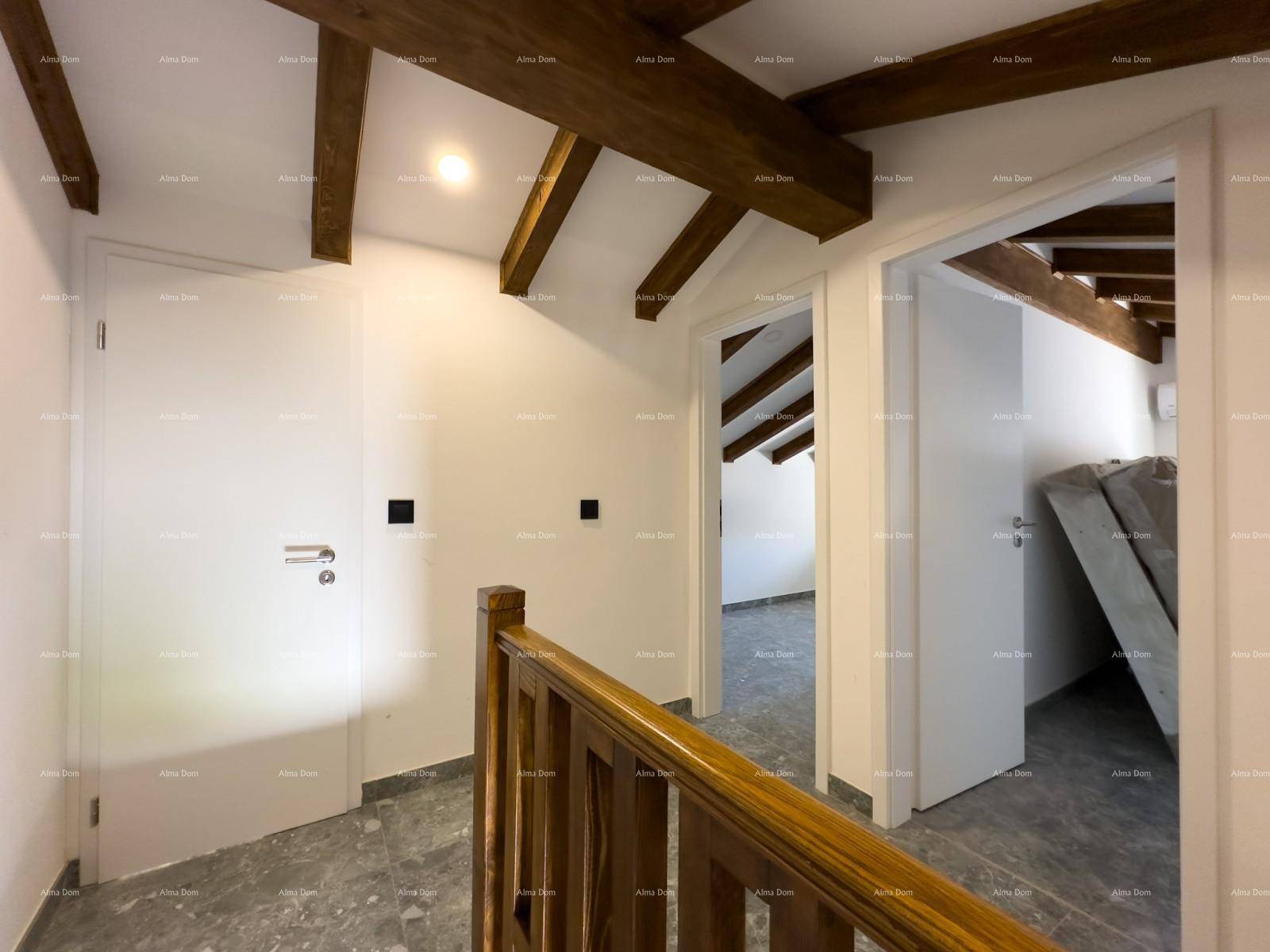 Heller Flur im Obergeschoss mit sichtbaren Holzbalken und grauen Fliesen, führt zu den Schlafzimmern.
