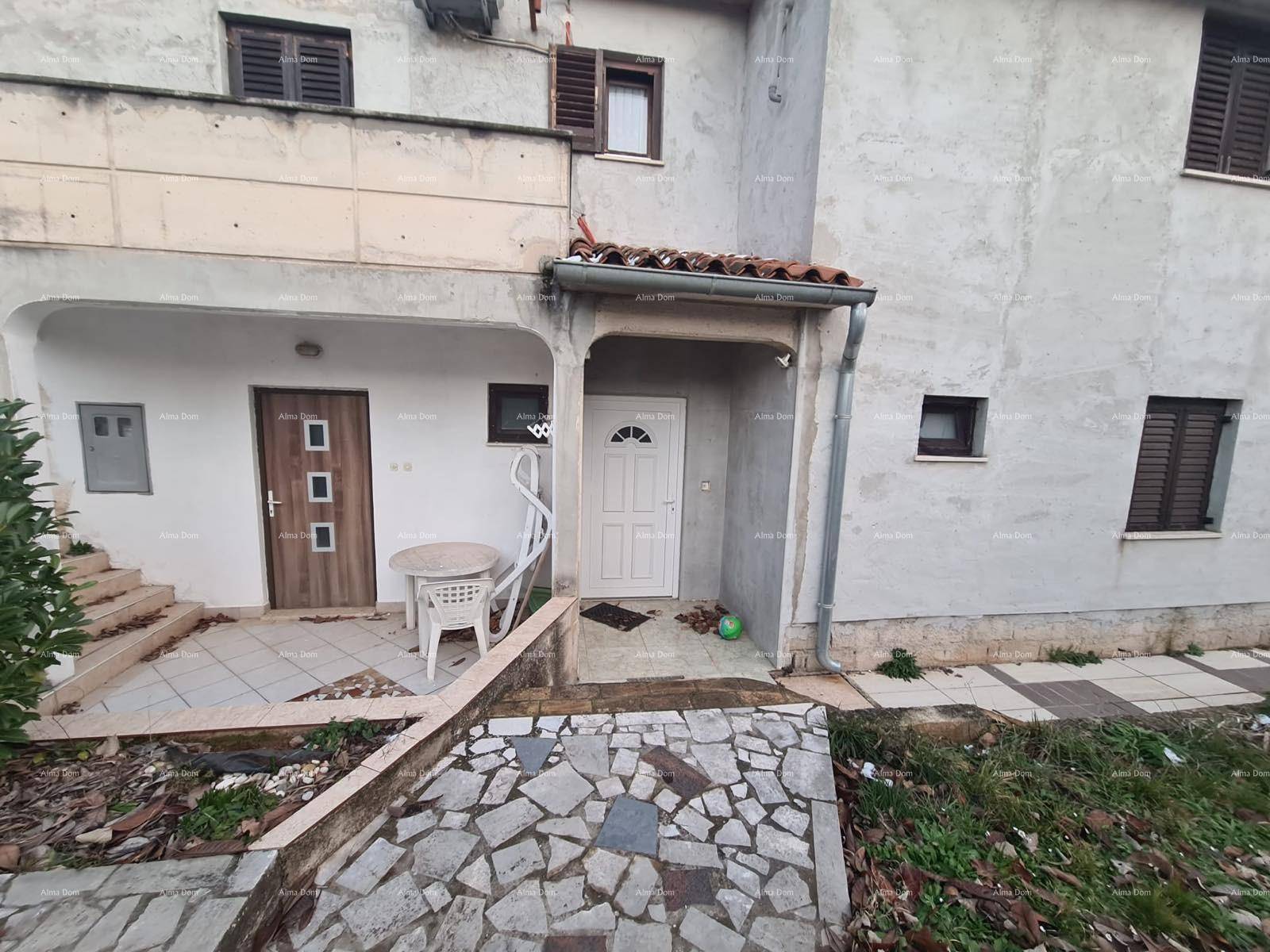 Vorderseite des Hauses mit zwei Eingängen, einer kleinen Terrasse und einem gefliesten Weg.