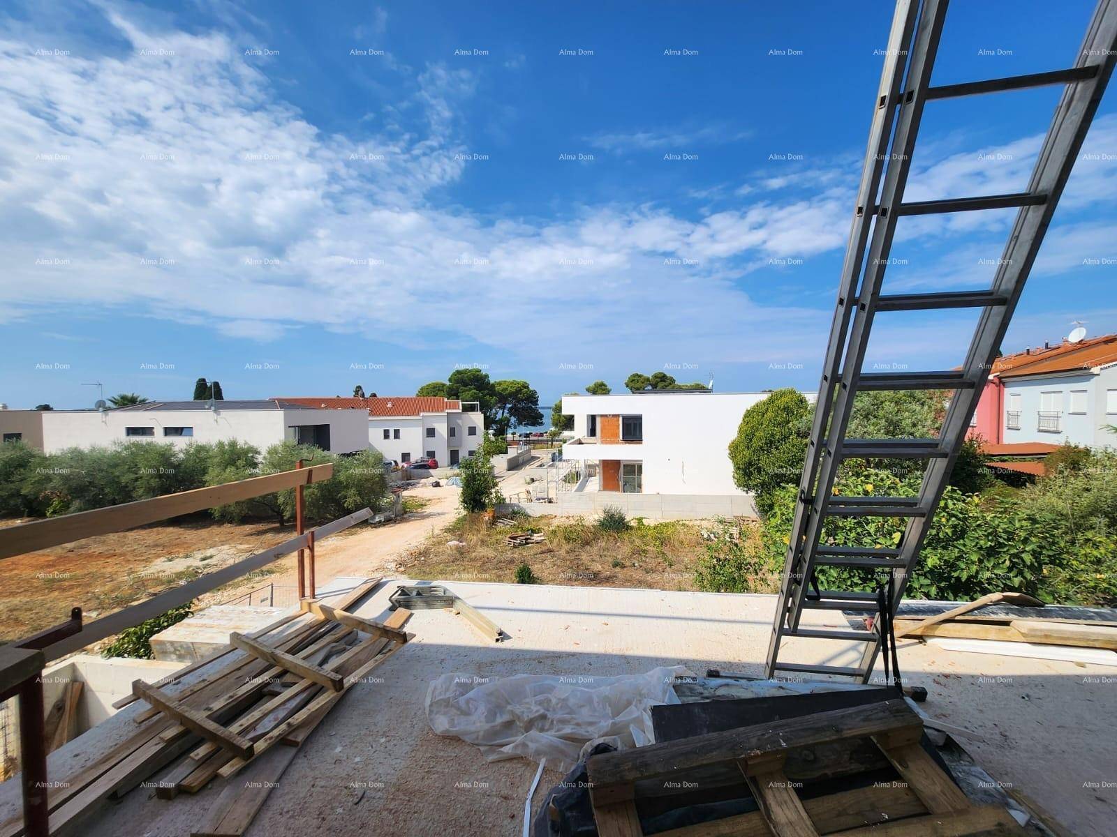 Blick von der Baustelle über ungenutztes Land zum Meer, mit Baumaterialien im Vordergrund.