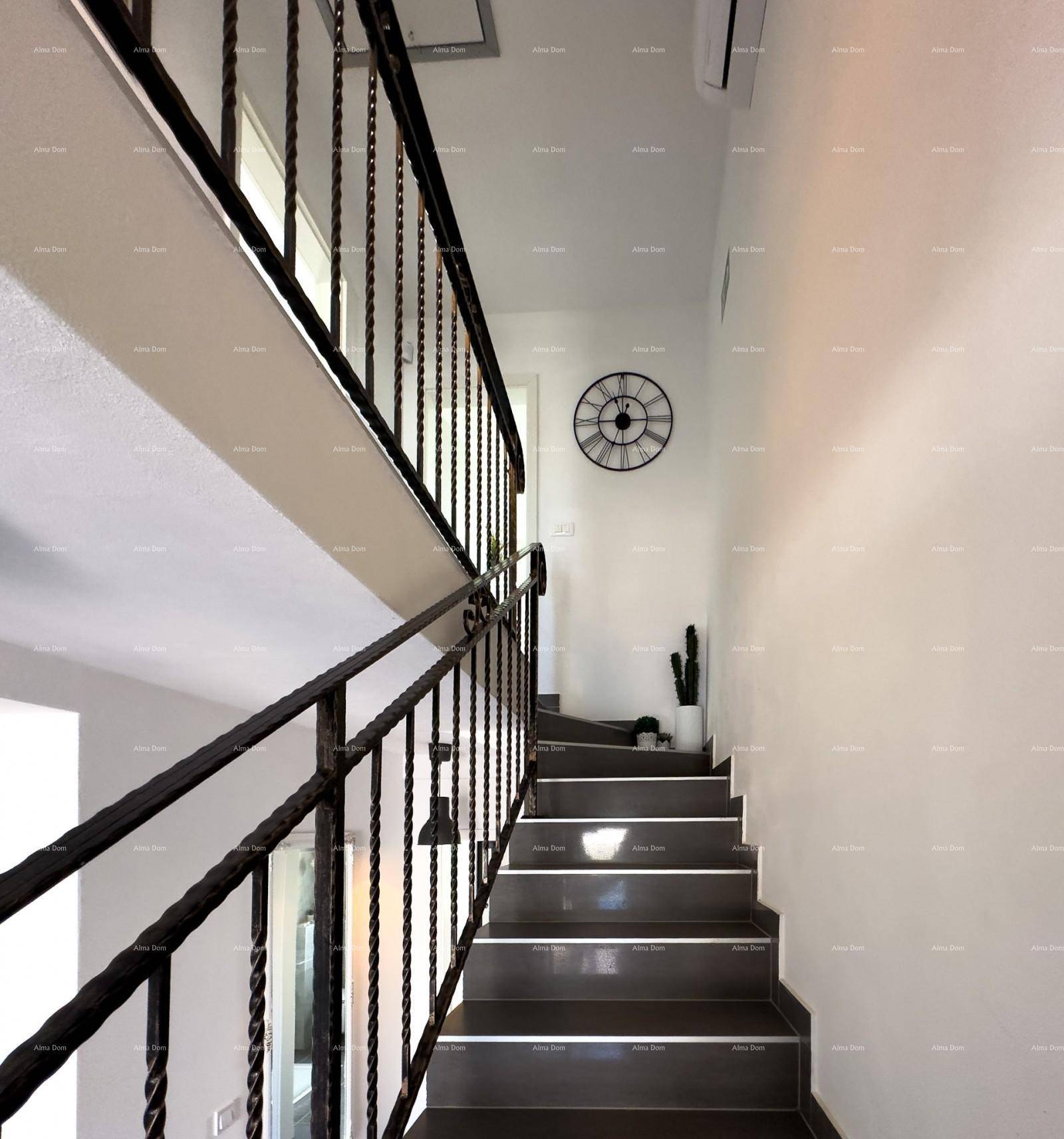 Treppenhaus mit schmiedeeisernem Geländer und dunklen Stufen, das in die obere Etage führt.