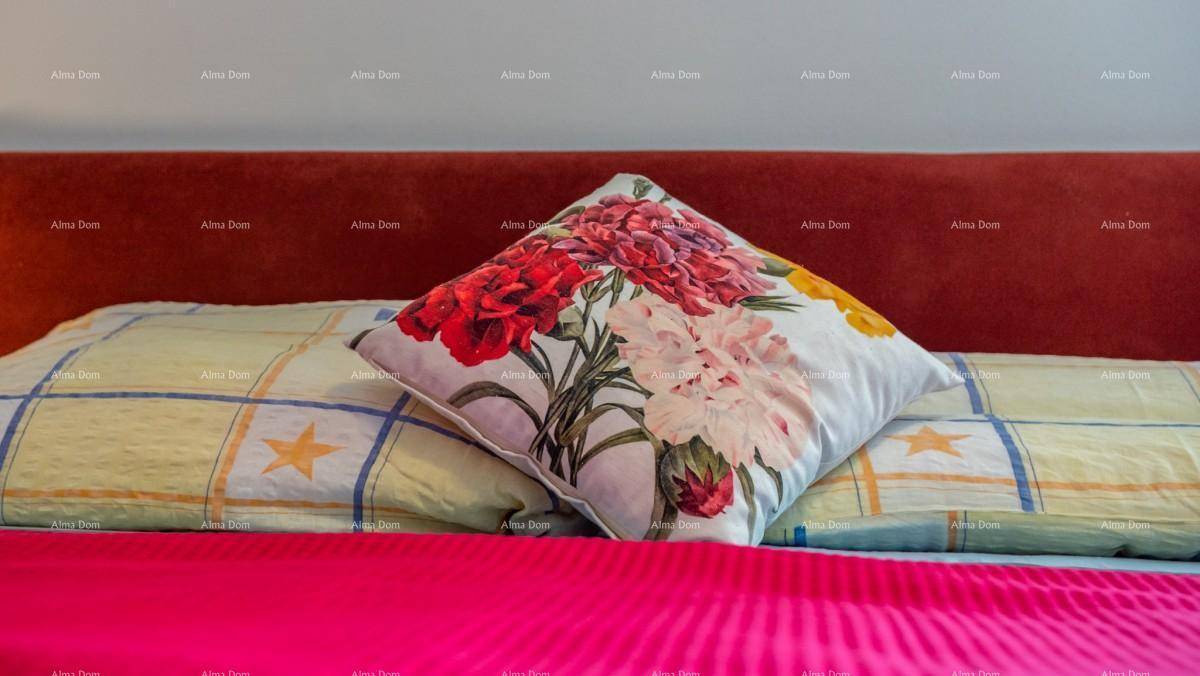 Dekoratives Kissen mit Blumenmuster auf einem Bett in einem Schlafzimmer.