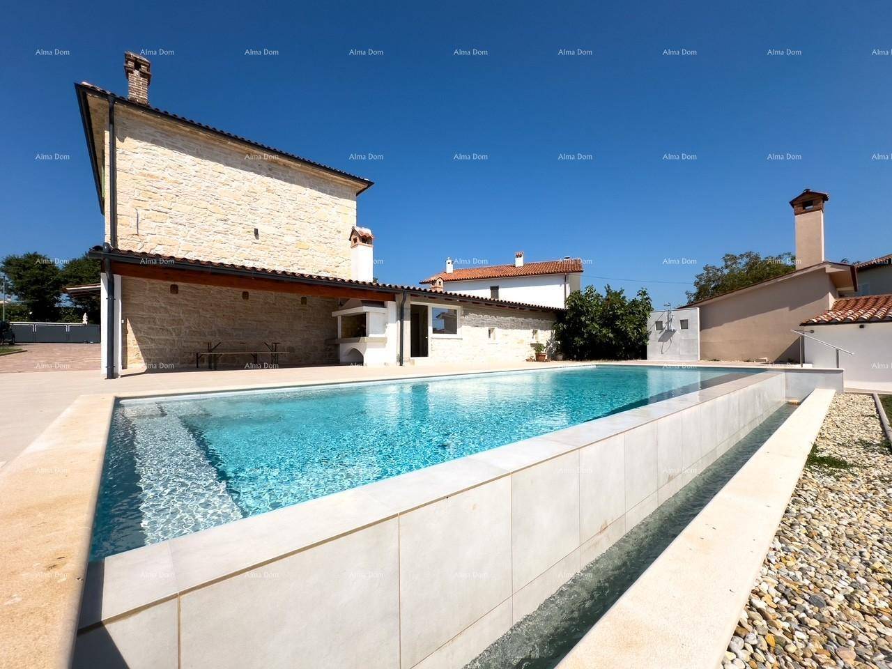 Moderner Swimmingpool mit gefliestem Rand und Grillbereich hinter dem Steinhaus.