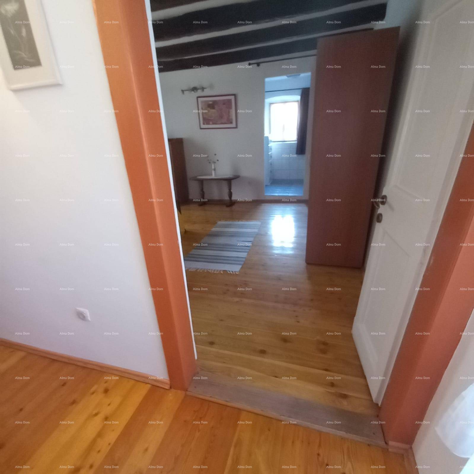 Blick durch eine Türöffnung in einen weiteren Raum mit Holzboden und einem Fenster, das Tageslicht hereinlässt.