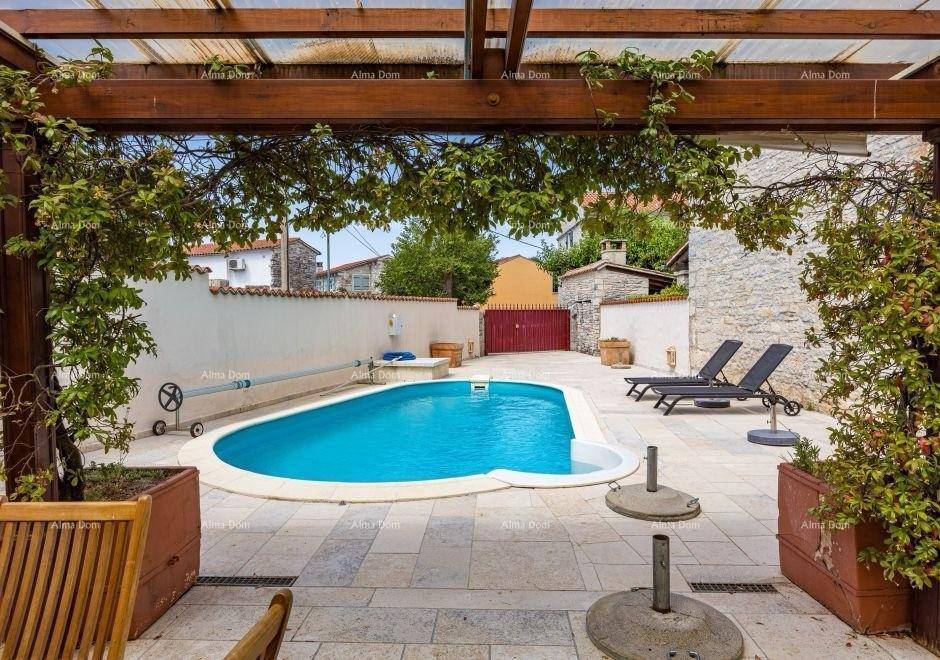 Blick auf den Poolbereich mit Liegestühlen und einem überdachten Essbereich von der Terrasse aus.