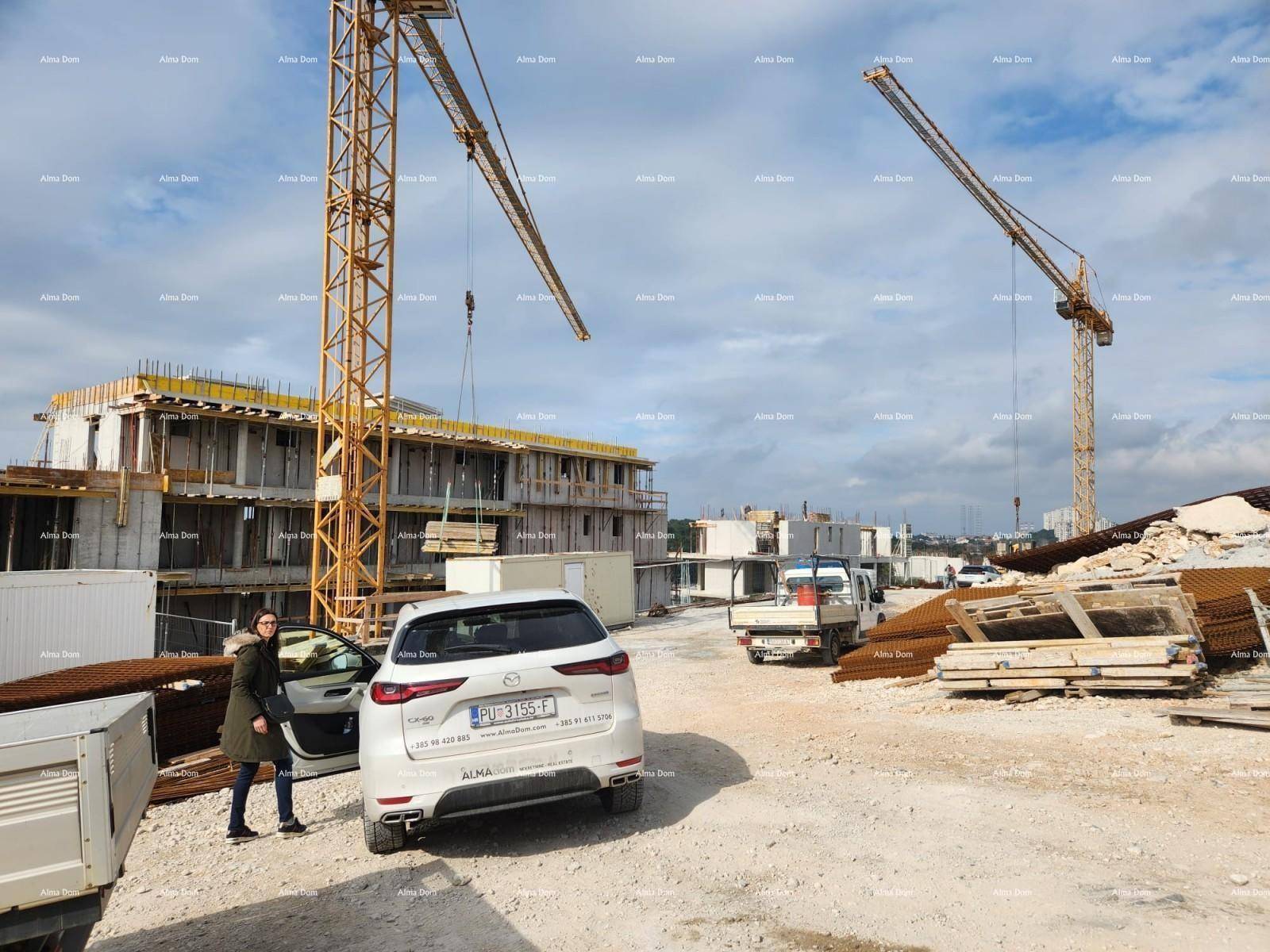 Baustelle mit großen Kränen und im Bau befindlichen Gebäuden unter bewölktem Himmel.