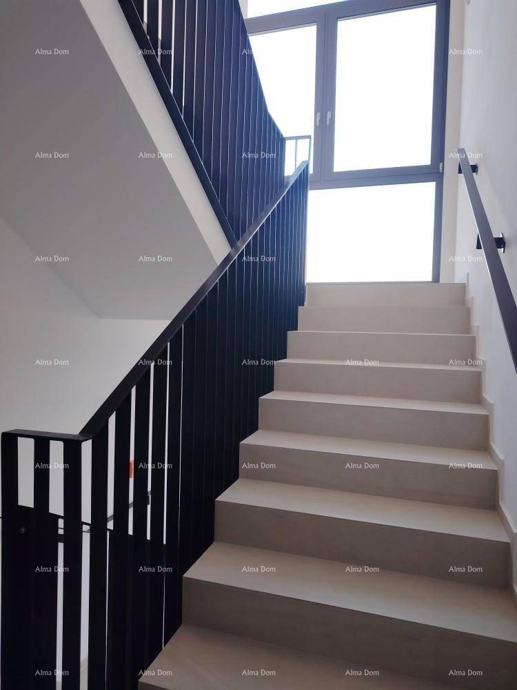 Moderne Treppe mit dunklem Geländer und großen Fenstern für viel Tageslicht.