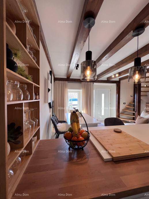 Detailansicht der modernen Küche mit Holztheke, Barhockern und Essbereich, unter stilvollen Pendelleuchten.
