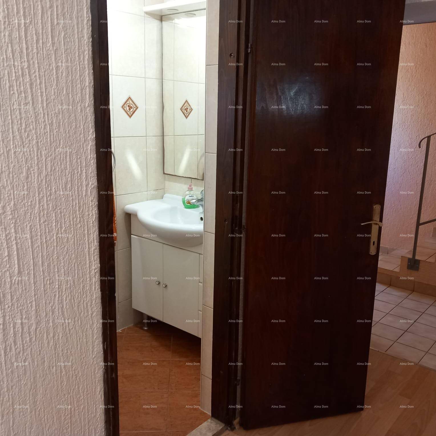 Badezimmer mit Waschtisch und Spiegel, vom Flur aus sichtbar.