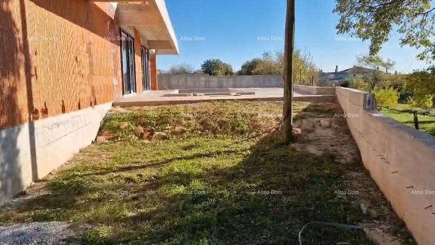Blick auf den Rohbau mit dem Gartenbereich und der vorbereiteten Betonterrasse unter blauem Himmel.