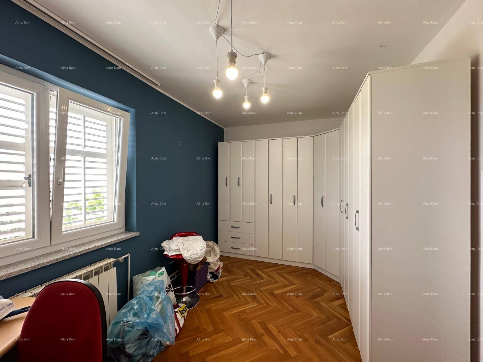Geräumiges Schlafzimmer mit blauer Wand, Fischgrätparkett und geschwungenem Kleiderschrank.