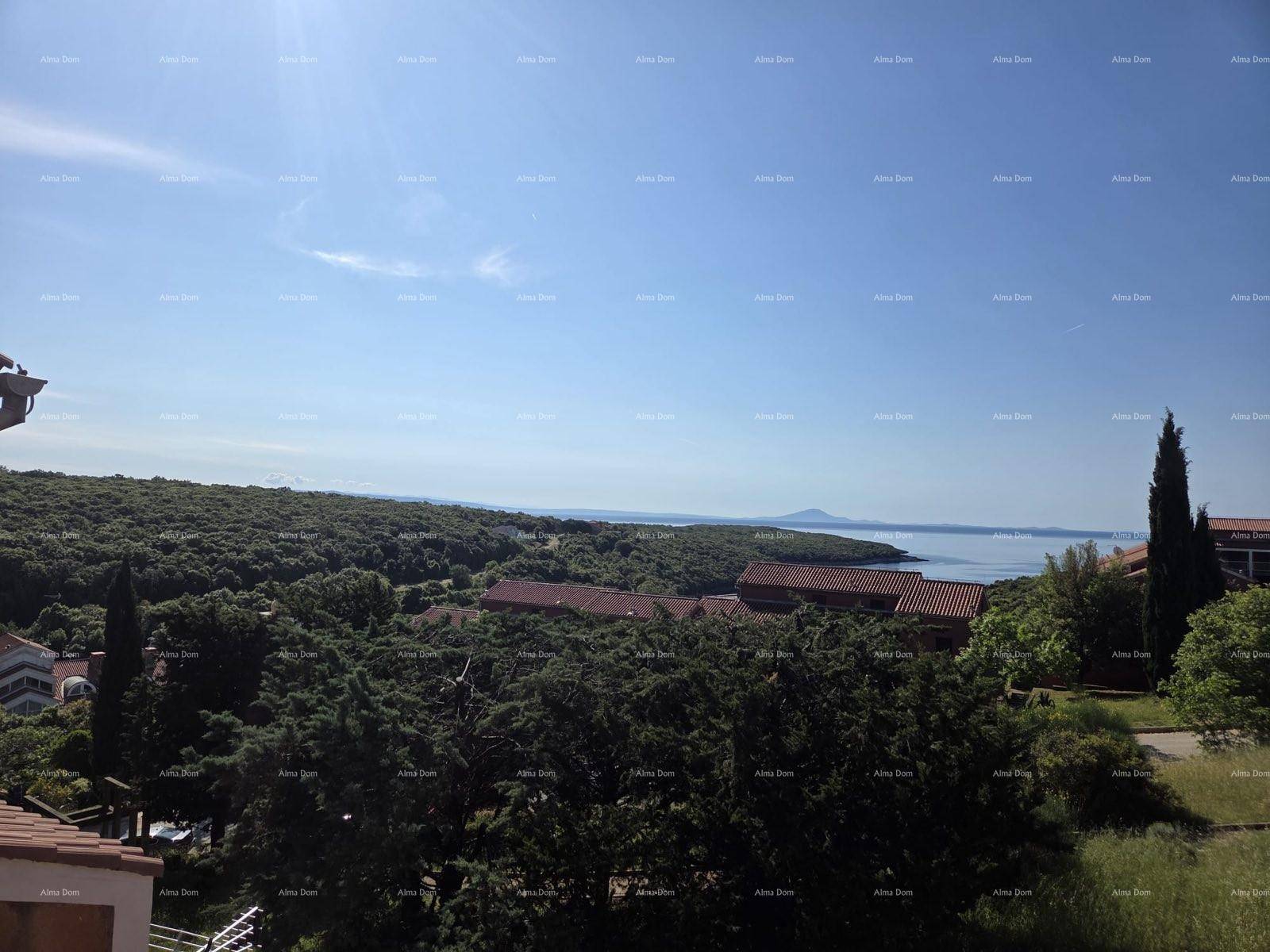 Weiter Blick über grüne Hügel, das Meer und die Küstenlandschaft unter blauem Himmel.