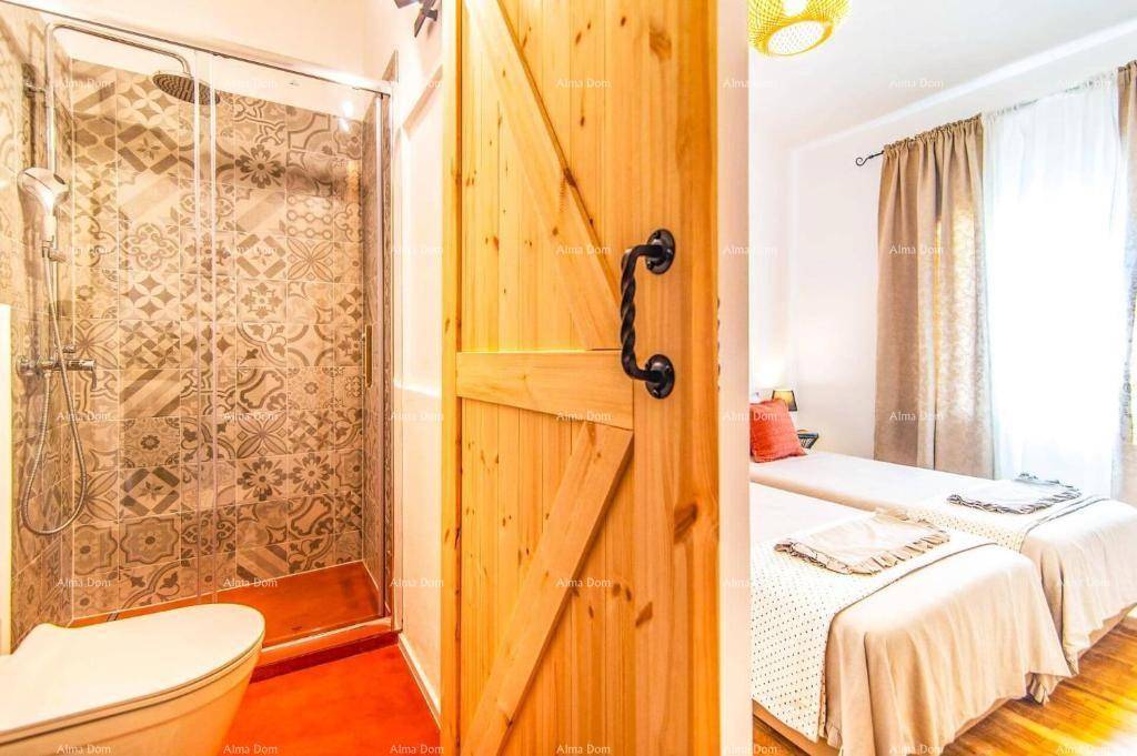 Modernes Badezimmer mit begehbarer Dusche, gemusterten Fliesen und Holztür zum Schlafzimmer.