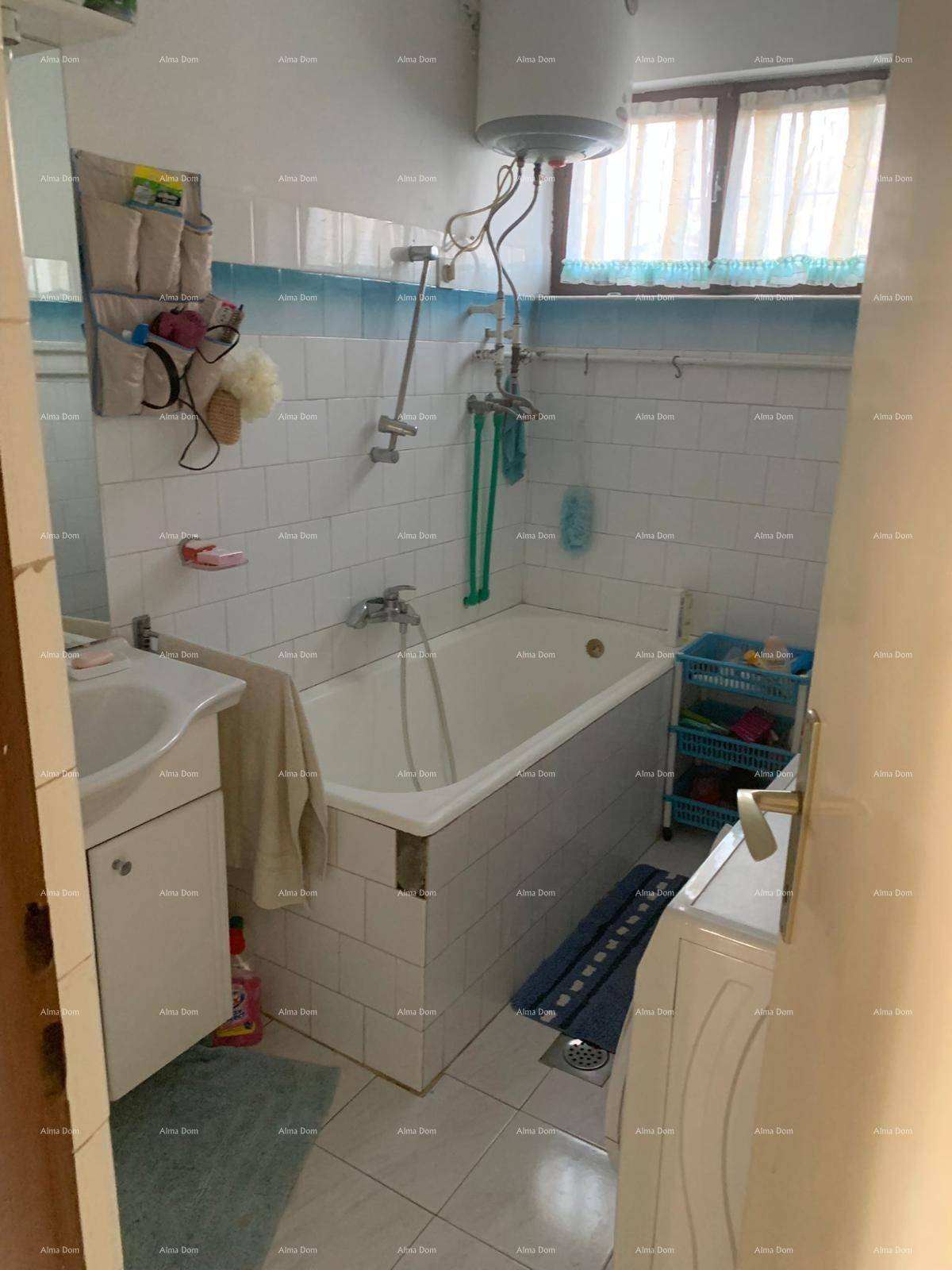 Badezimmer mit Badewanne, Waschbecken, Fliesen an Wänden und Boden sowie einem Fenster für Tageslicht.