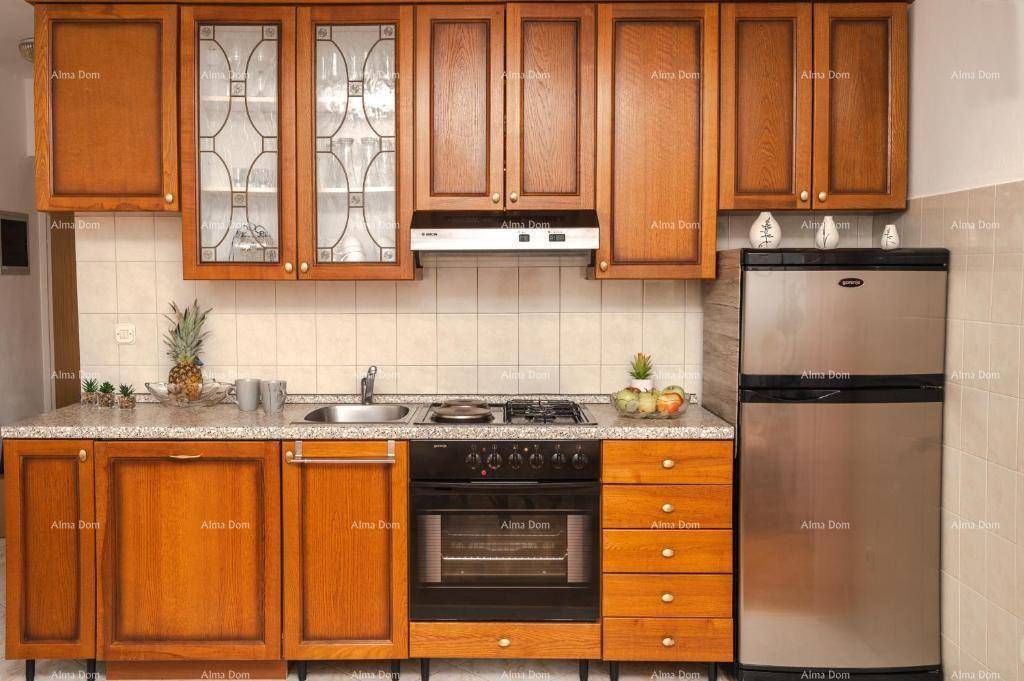 Klassische Einbauküche mit holzfarbenen Schränken, integriertem Gasherd und Backofen sowie Fliesenboden.
