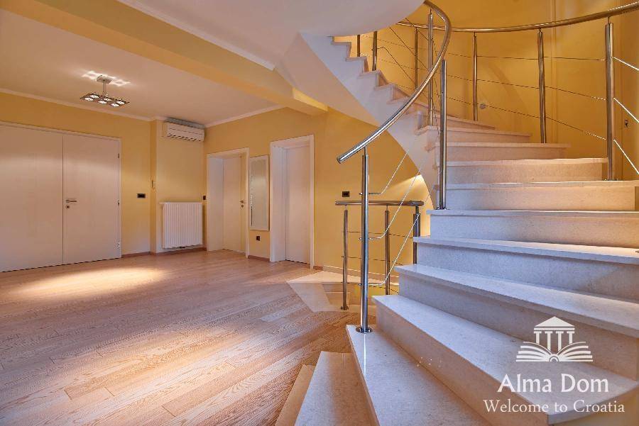 Heller offener Wohnbereich mit eleganter Wendeltreppe und Holzboden.