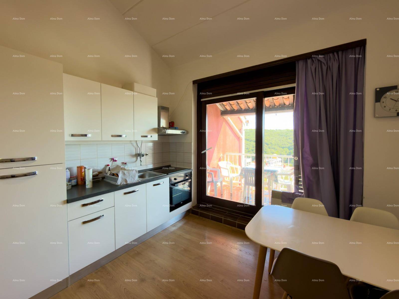 Kleine Küche mit weißen Schränken und Essbereich, direktem Zugang zum Balkon.