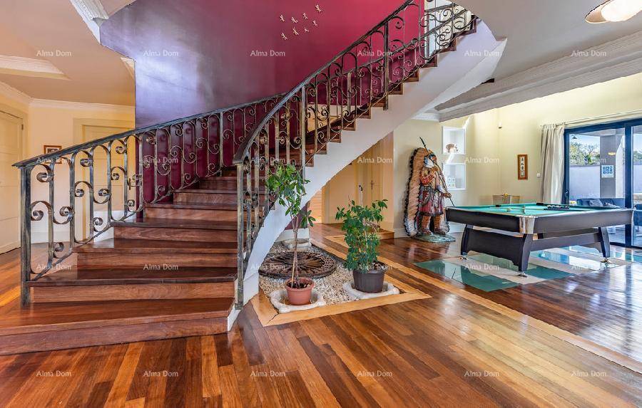 Elegante Holztreppe mit schmiedeeisernem Geländer und Billardtisch im Eingangsbereich.