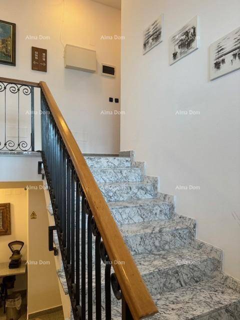 Elegante Marmortreppe mit schmiedeeisernem Geländer und Holzhandlauf in einem hellen Treppenhaus.