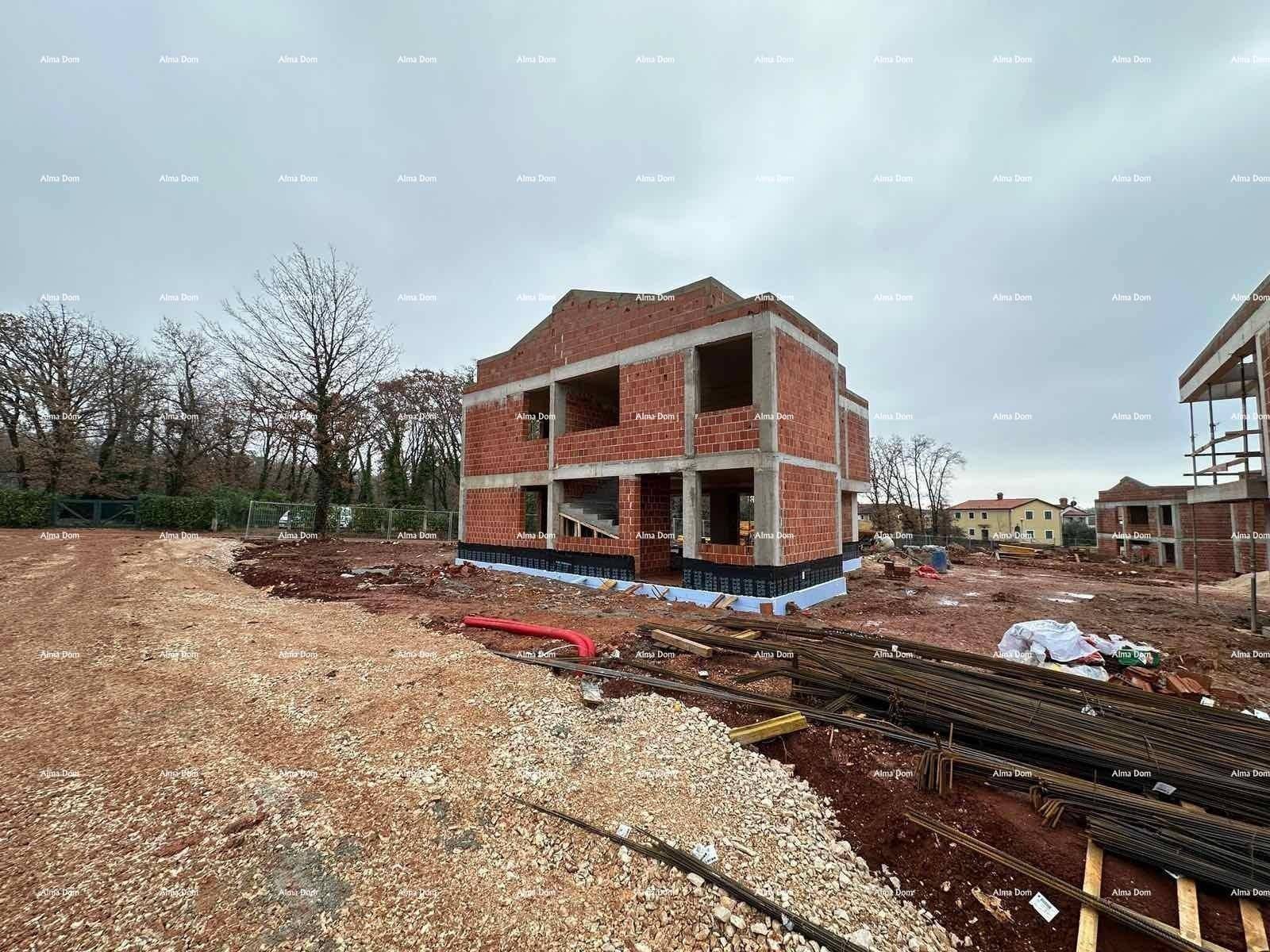 Rohbau eines Hauses mit Ziegelwänden und Betonfundament auf einer Baustelle.