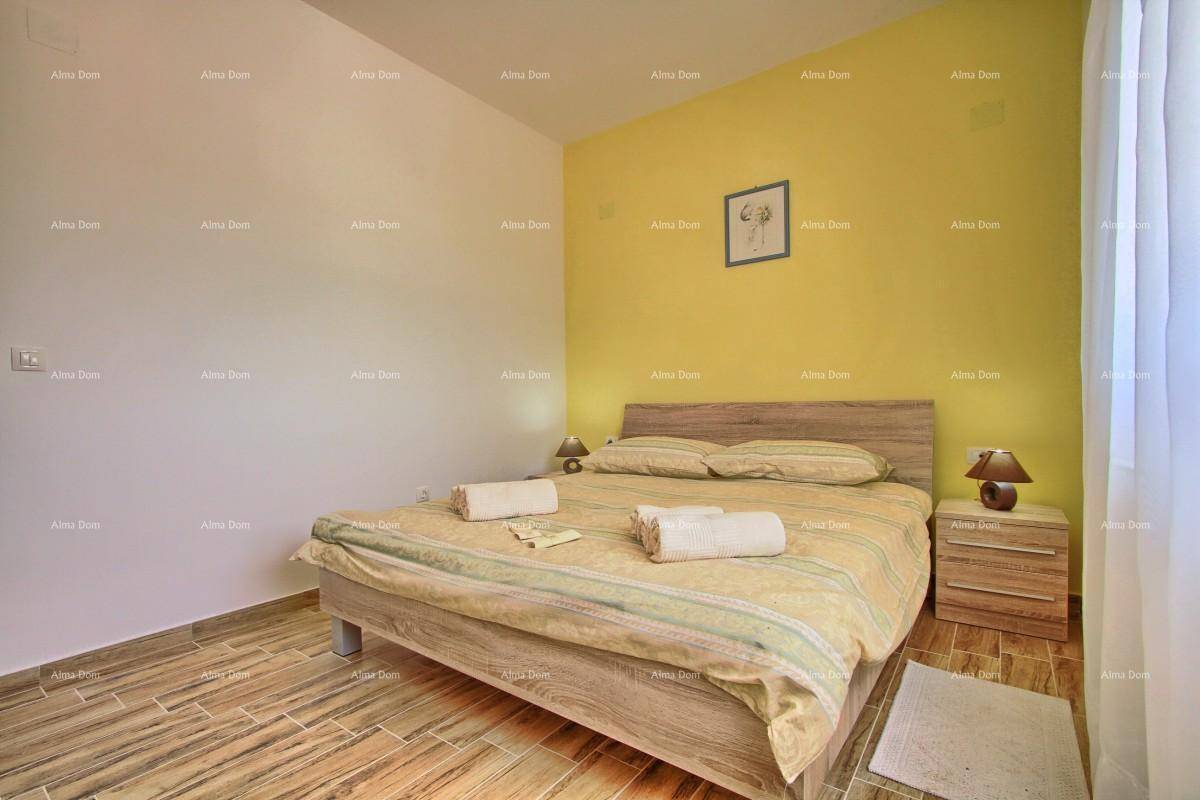 Schlafzimmer mit Doppelbett, gelber Akzentwand und Fliesen in Holzoptik.