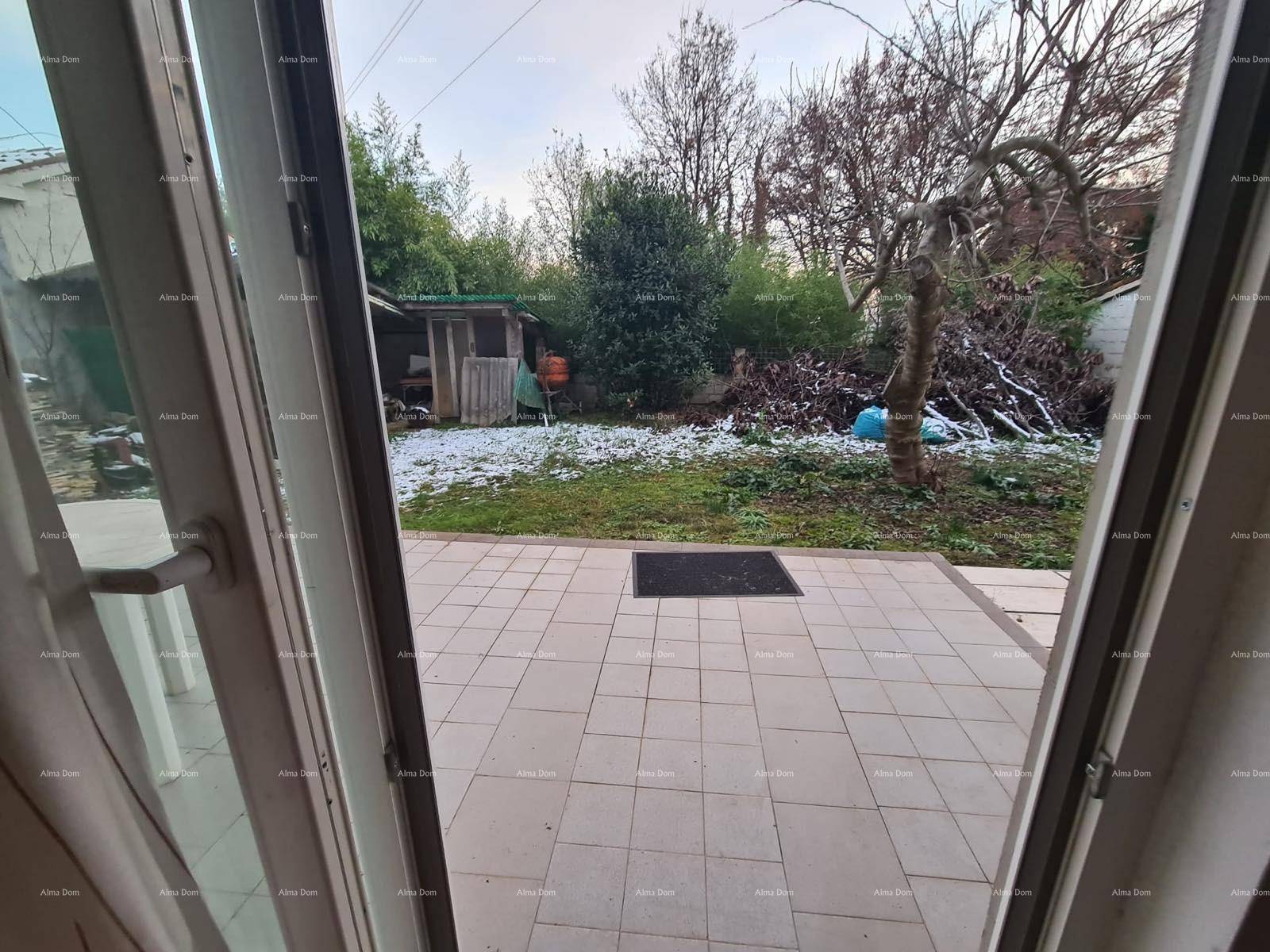 Blick aus dem Fenster auf einen Gartenbereich mit Terrasse und Schuppen im Winter.