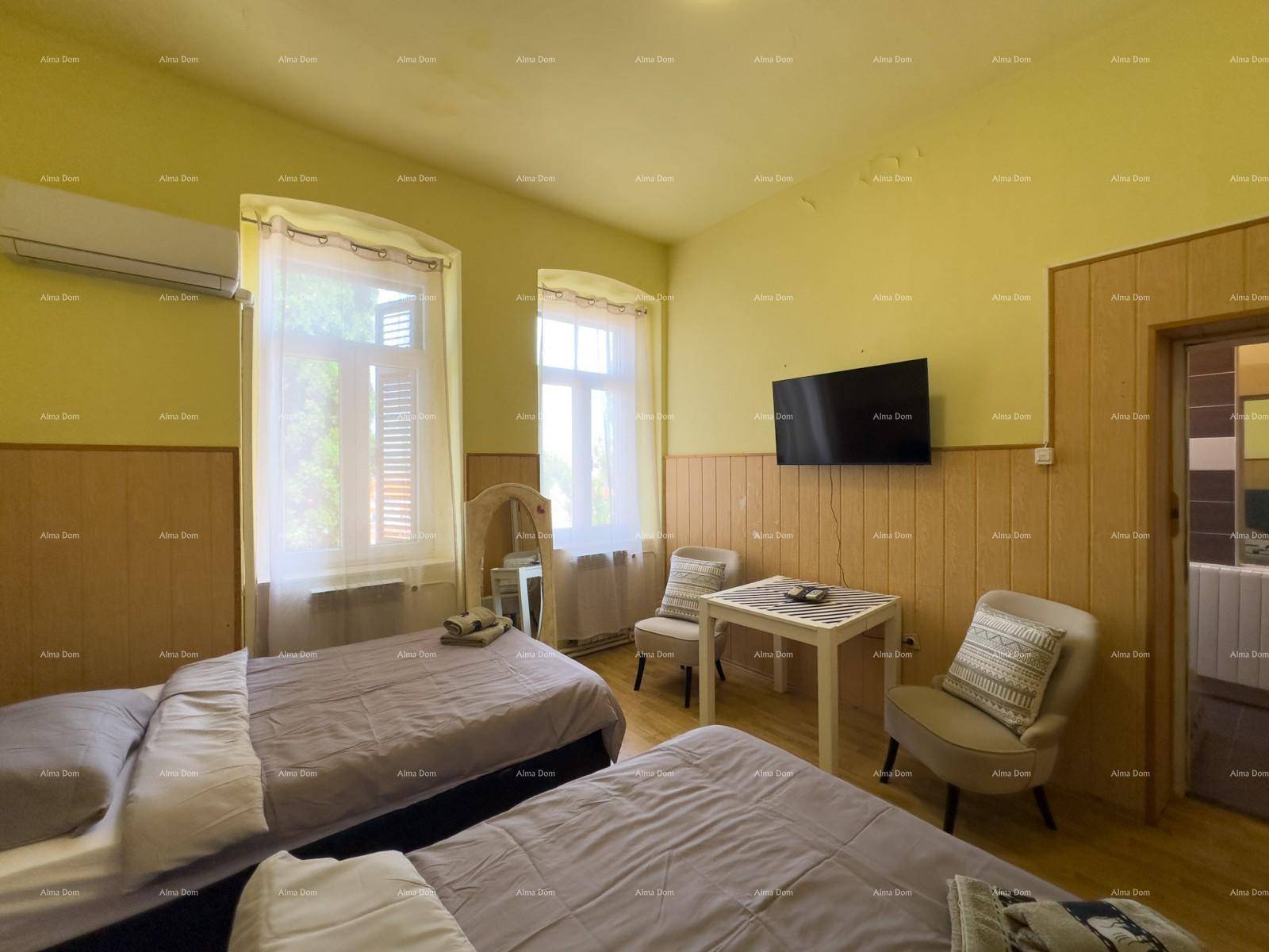 Helles Schlafzimmer mit zwei Einzelbetten, Tisch und Fenstern mit Blick ins Grüne.